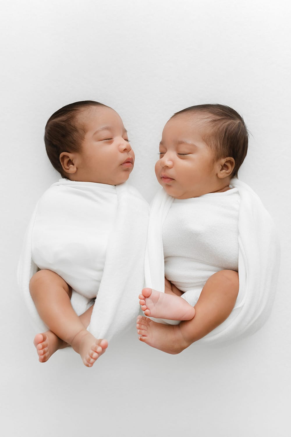 A Newborn Photography in Virginia photo of twin newborn baby girls swaddled on a white blanket
