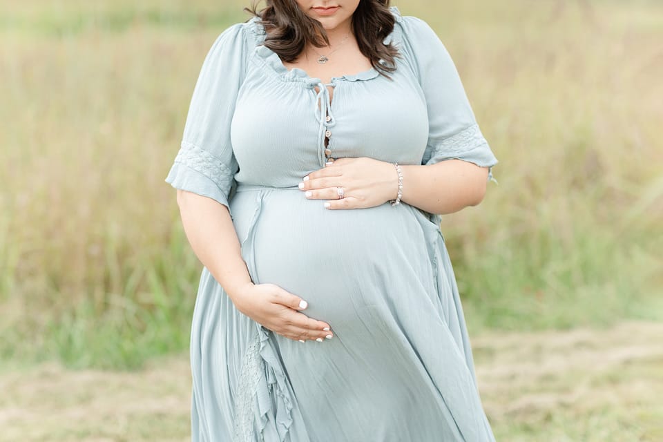 A pregnant mother holding her belly by Virginia Maternity Photographer